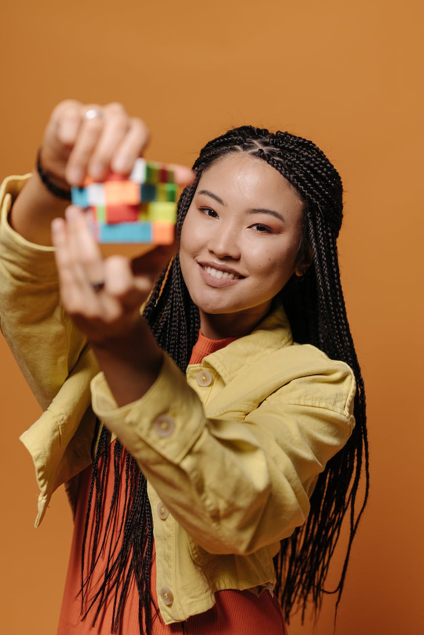 a woman in yellow jacket holding a rubik s cube